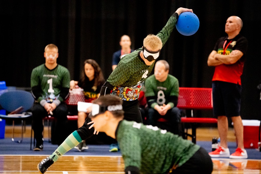 A goalball player from Lithuania extends his arm back during a throw