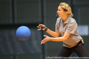 A female referee throws the goalball during a match