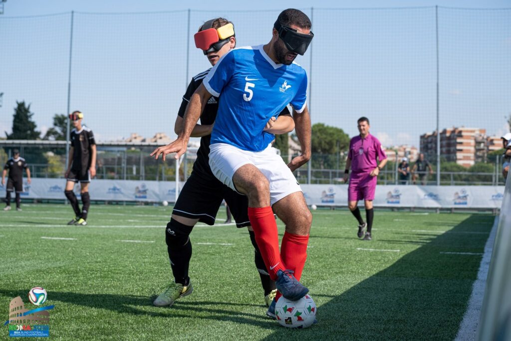 Hakim Arezki guards the ball with his right foot under pressure from a German opponent at the 2019 IBSA Blind Football European Championships in Rome, Italy 