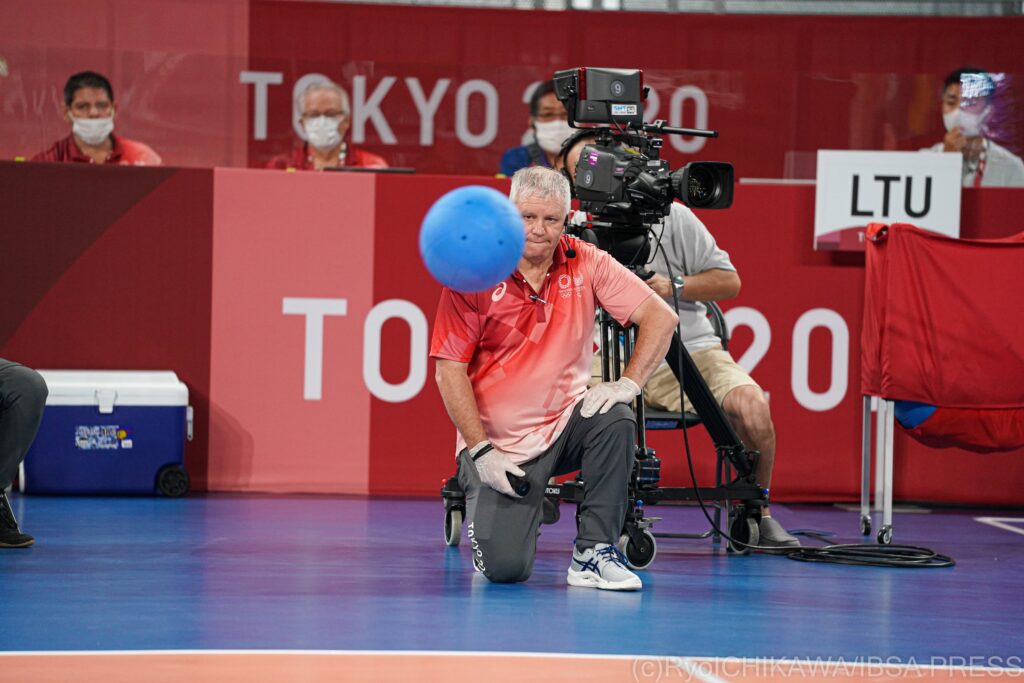 A goalball referee kneels on the court in order to assess the position of the ball at the Tokyo 2020 Paralympic Games