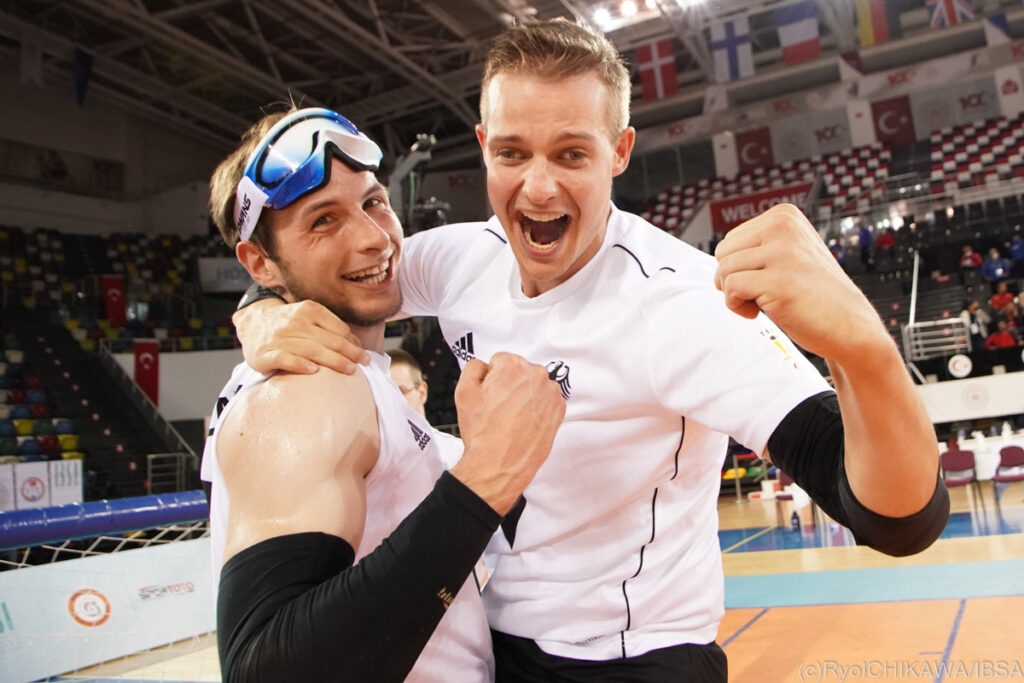 Two German goalball players smile for the camera and clench their fists in celebration