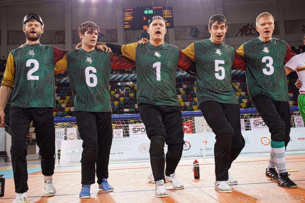 The Lithuanian men's goalball team link arms in a line to celebrate after winning a match