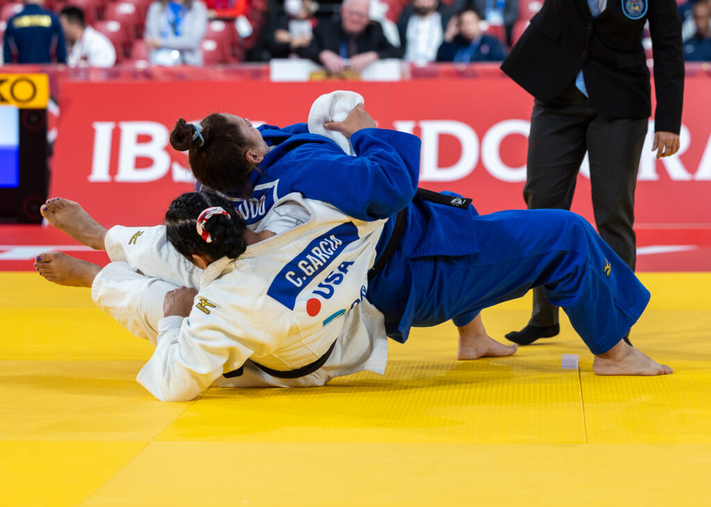 Two female judoka grapple on the mat