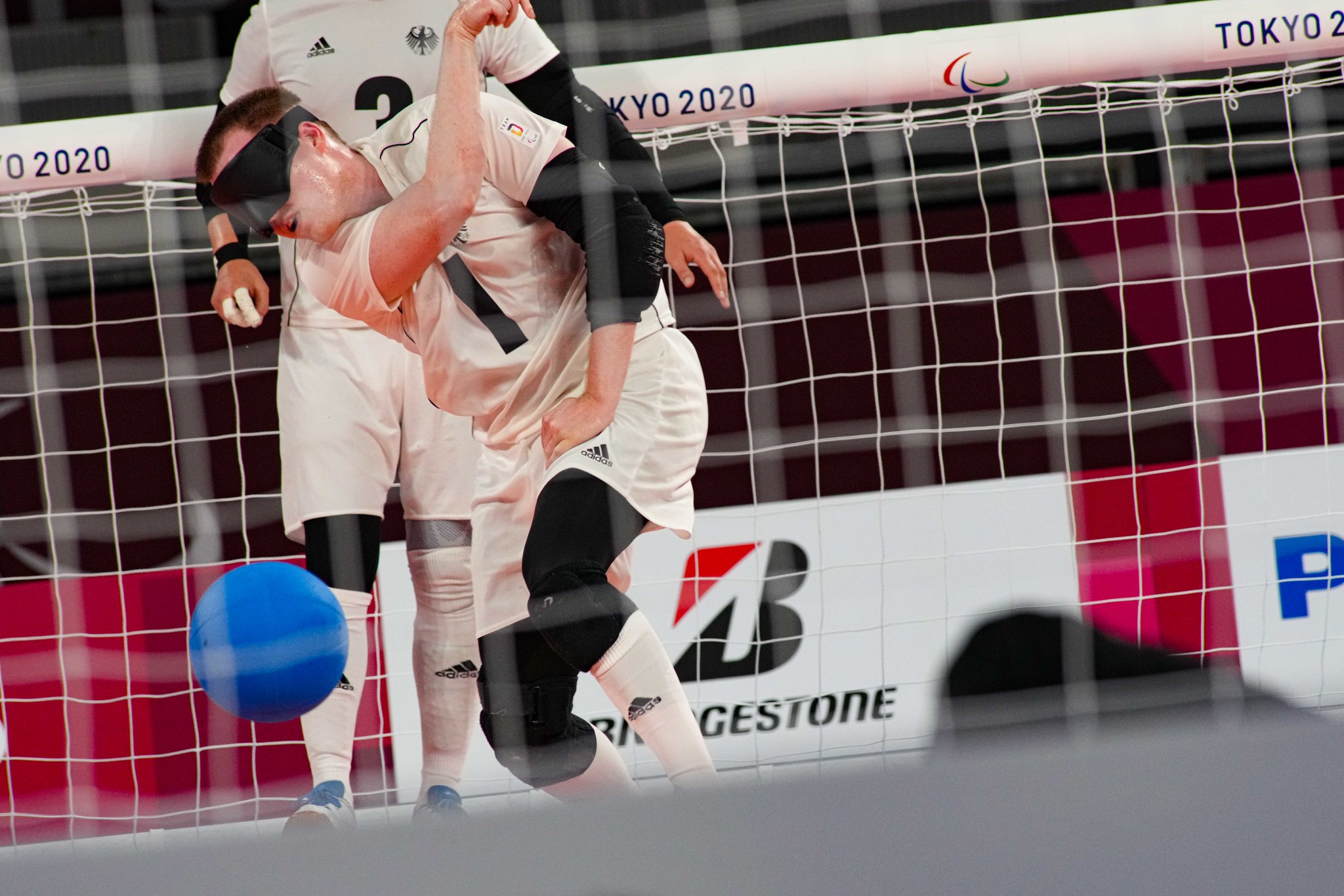 soaked in sweat, Michael Dennis of Germany flings the goalball across the court